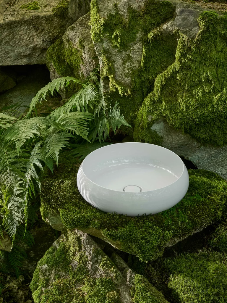 Lavabo BetteCraft bianco su una roccia ricoperta di muschio, circondato da arbusti verdi e pietre naturali.