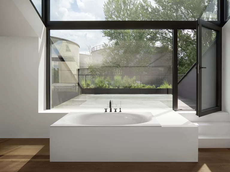 BetteEve: Bañera empotrada en un suelo de madera frente a una ventana frontal.