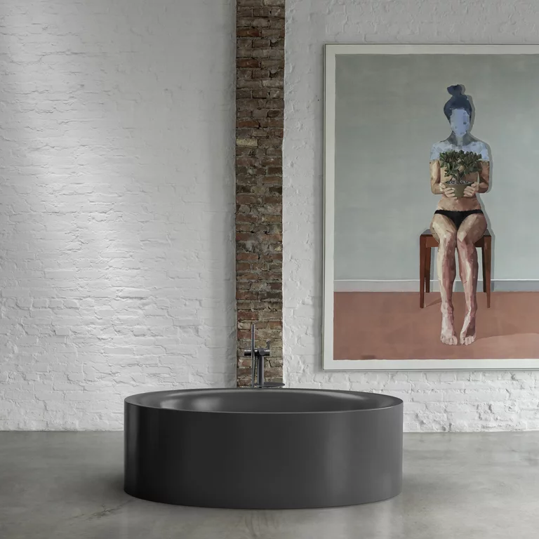 BetteEve Oval Silhouette: черная, отдельно стоящая ванна перед белой кирпичной стеной с большой картиной.