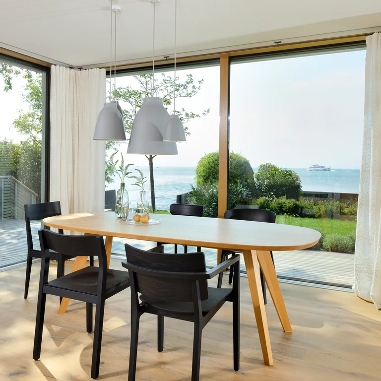 Dining area in the show house "Haus am See", Lake Constance. The dining area in the show house "Haus am See", Lake Constance, with a view through the glazed south side and interior made of natural materials.