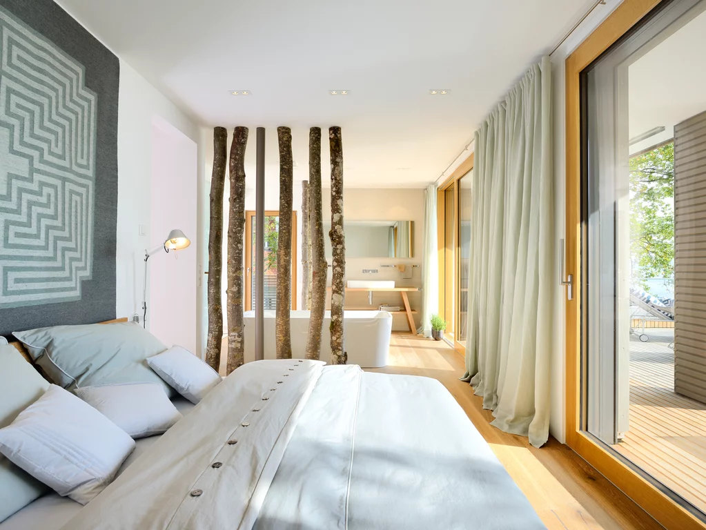 Bedroom in the show house "Haus am See", Lake Constance. The bedroom in the show house "Haus am See", Lake Constance, with a view through the generous window front and natural interior.