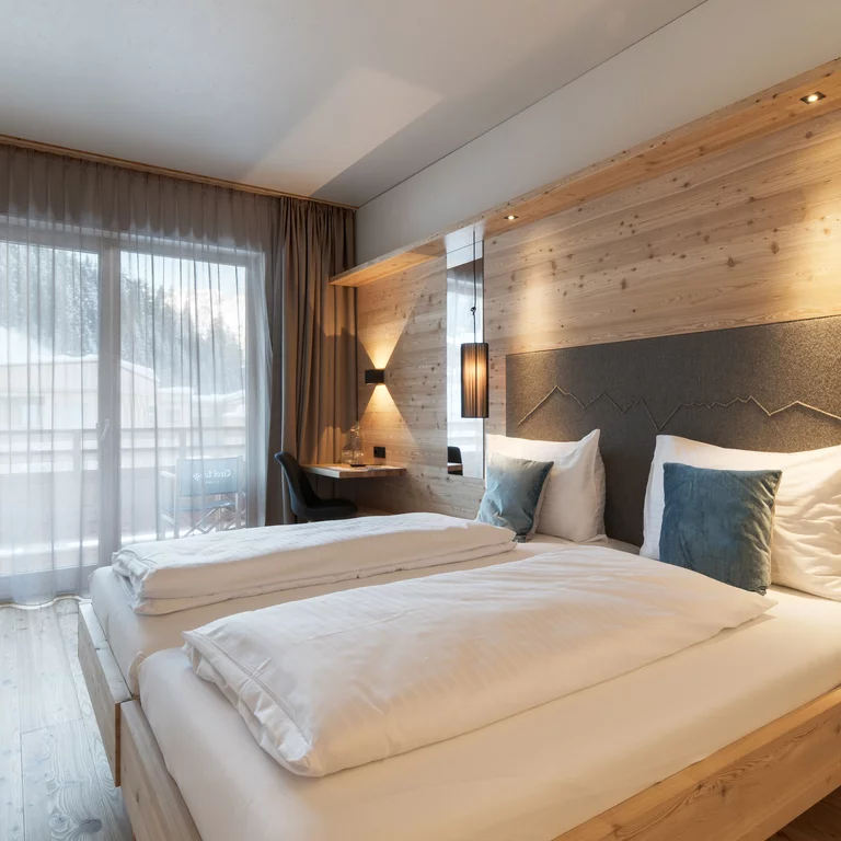 Bedroom in the wooden Tirol Lodge, Austria. The bedrooms of the wooden Tirol Lodge, Austria, appear calm and inviting due to the natural materials and the clear design.