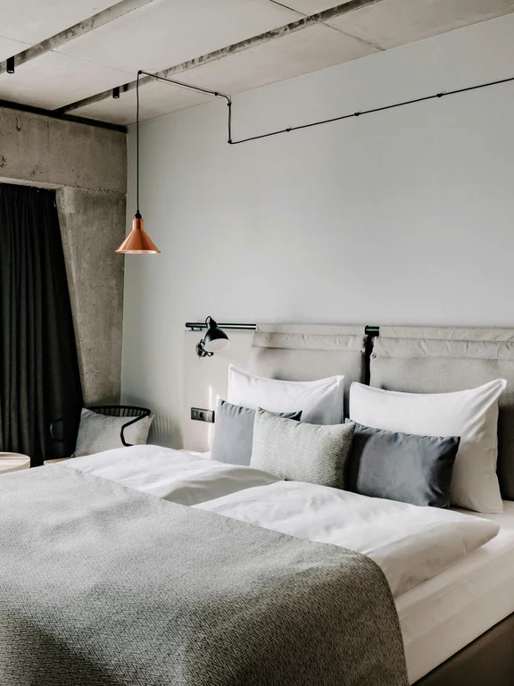 Bedroom at the Vienna House Mokotow, Warsaw. The bedrooms at Vienna House Mokotow, Warsaw, combine materials such as concrete, wood and wool with warm tones.