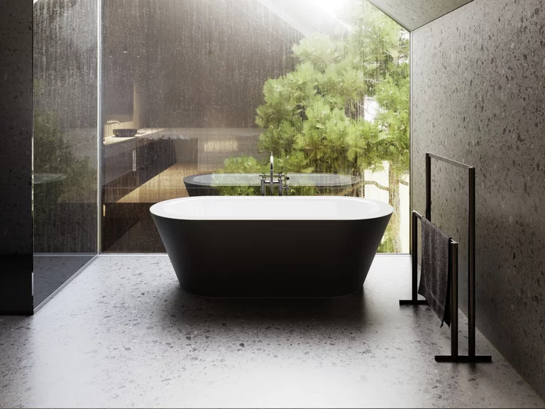 Vrijstaand zwart bad voor groot raam met uitzicht op bomen, moderne ruimte met schuine plafond en stenen vloer.