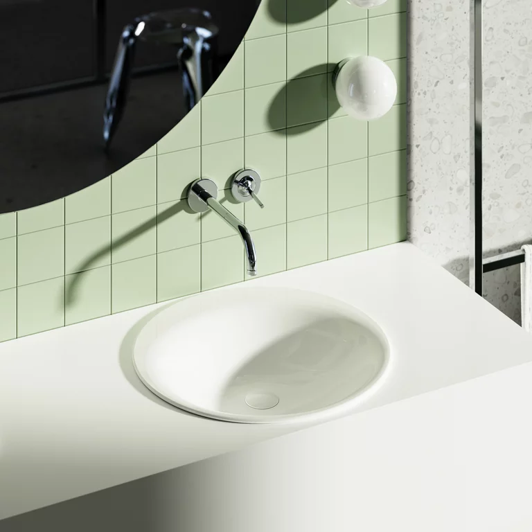 Modernes Waschbecken mit runder Einbauschale, Wandarmatur und grün gefliester Rückwand unter einem großen Spiegel.