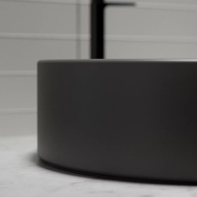 Vasque à poser BetteSuno en gros plan, de couleur graphite, avec une cuvette ronde posée sur un plan de travail clair, avec en arrière-plan une décoration murale minimaliste et des détails de robinetterie noirs.