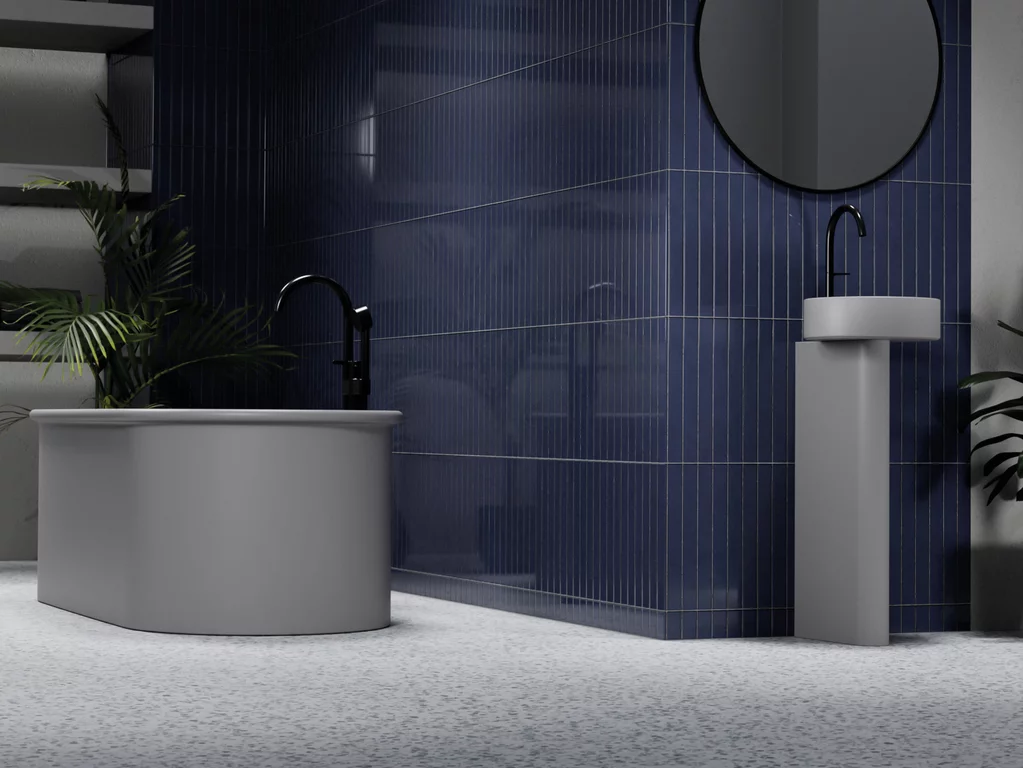 Baignoire autoportante BetteSuno en argent élégant avec une robinetterie noire, devant un mur de carrelage bleu foncé brillant, combinée avec un lavabo BetteSuno Pedestal et des plantes d'intérieur discrètes dans une salle de bains stylée.