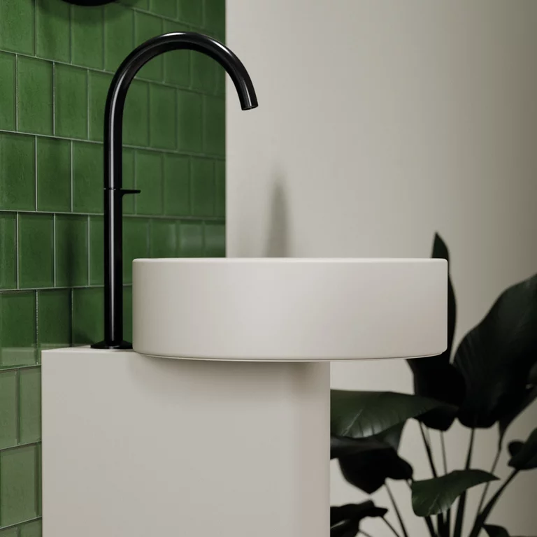 Vasque BetteSuno Pedestal de couleur flax avec vasque ronde et robinetterie noire, placée devant un mur de carreaux verts brillants.