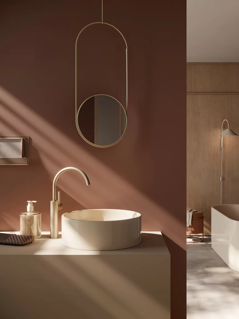 Moderne BetteBalance opzetwastafel in de kleur bahama beige met een elegante gouden kraan. Op de achtergrond zijn warme bruintinten en subtiel daglicht te zien.