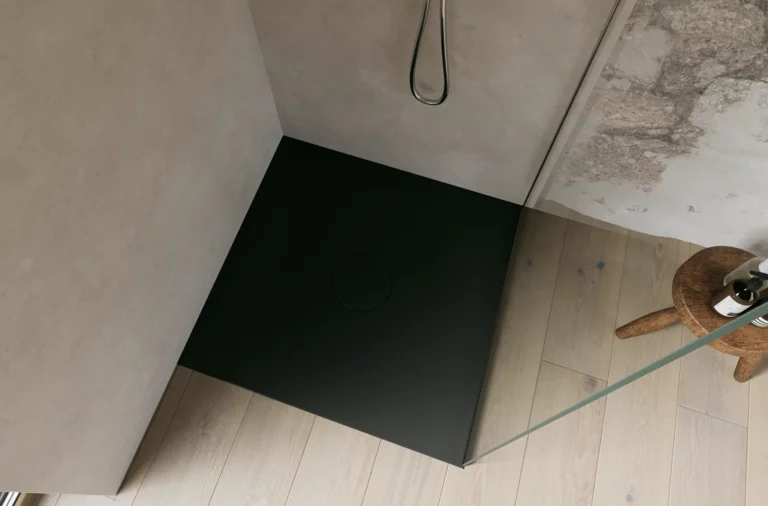 Zwarte inloopdouchebak met glazen wand en zwarte douche, schuin van boven gefotografeerd.