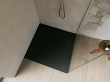 Zwarte inloopdouchebak met glazen wand en zwarte douche, schuin van boven gefotografeerd.