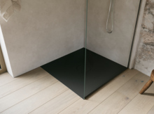 Zwarte inloopdouchebak met glazen wand en zilverkleurige douche in een lichte, minimalistische badkamer.