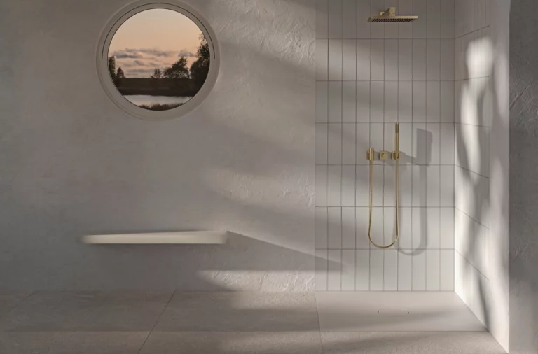 Flat rectangular steel enamel shower tray in bright, accessible shower with round window and large rain showerhead.