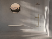 Flat rectangular steel enamel shower tray in bright, accessible shower with round window and large rain showerhead.