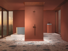 Freestanding round steel-enamel bathtub, central shower, washbasin on cylindrical countertop to the right, modern bathroom.