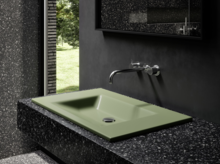 Зелёная прямоугольная стальная эмалированная раковина на чёрной столешнице, настенный смеситель, современная ванная с окном.