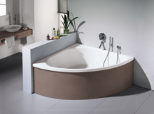 Baignoire en acier émaillé angulaire avec façade arrondie, robinetterie indépendante, lavabo sur plan en bois en arrière-plan.