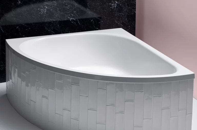 Baignoire rectangulaire en acier émaillé à façade courbée, surface blanche, devant un mur noir et rose.