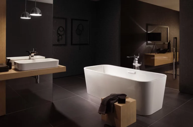 Freistehende, rechteckige Badewanne aus Stahl-Email und rechteckiges Waschbecken auf Einbauplatte in modernem Badezimmer.