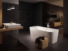 Freistehende, rechteckige Badewanne aus Stahl-Email und rechteckiges Waschbecken auf Einbauplatte in modernem Badezimmer.
