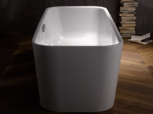 Отдельностоящая ванна из стальной эмали прямоугольной формы на деревянном полу, на заднем плане стопки книг.