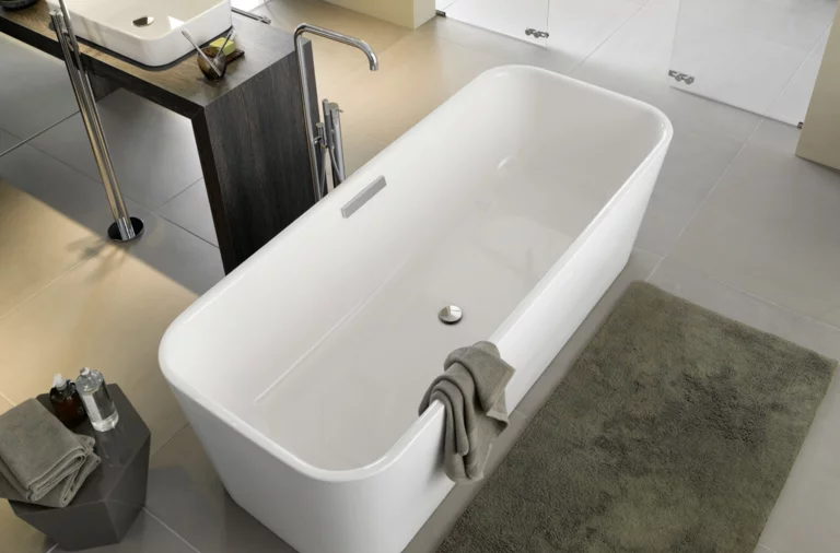 Русский: Отдельностоящая прямоугольная ванна из стальной эмали, рядом квадратная раковина на тёмной столешнице, современная ванная.