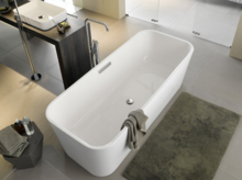 Русский: Отдельностоящая прямоугольная ванна из стальной эмали, рядом квадратная раковина на тёмной столешнице, современная ванная.