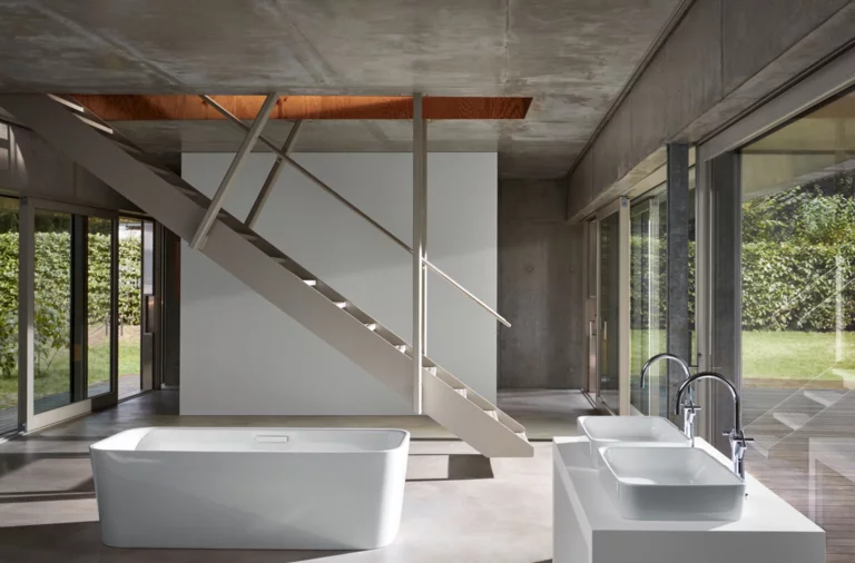 Отдельностоящая прямоугольная стальная эмалированная ванна и две прямоугольные раковины на встроенной панели в современной ванной.