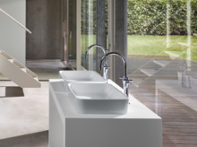 Deux lavabos rectangulaires en acier émaillé sur plan blanc avec robinetterie moderne, grandes fenêtres en arrière-plan.