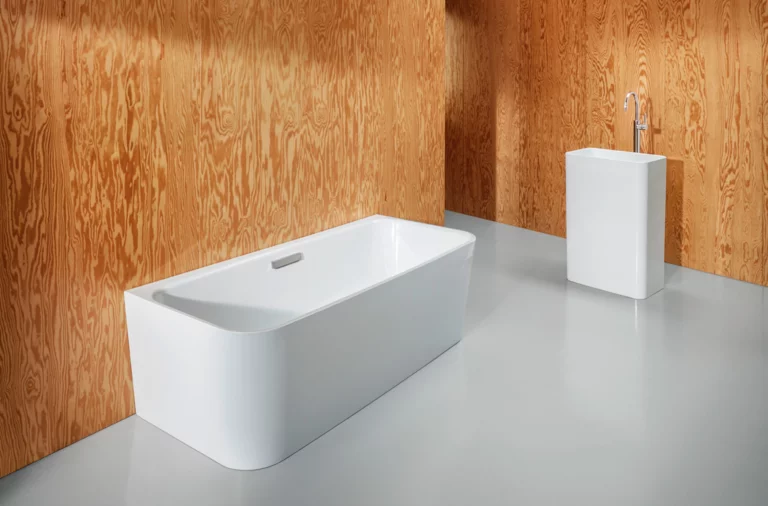 Freestanding rectangular steel enamel bathtub and rectangular washbasin, both with rounded corners.