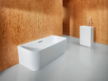 Freestanding rectangular steel enamel bathtub and rectangular washbasin, both with rounded corners.
