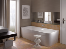 Vasca da bagno rettangolare autoportante in acciaio smaltato, accanto lavabo su piano d’appoggio scuro, bagno moderno.