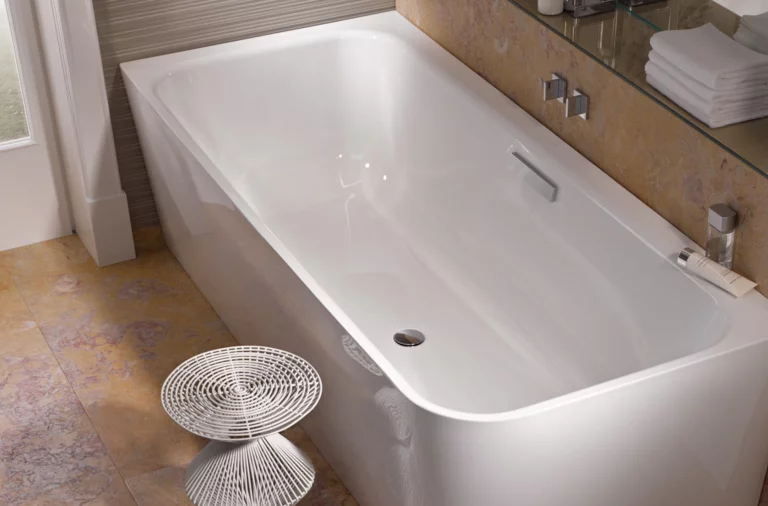 Vasca da bagno rettangolare in acciaio smaltato bianco con angoli interni arrotondati, bagno moderno con asciugamani e sgabello.
