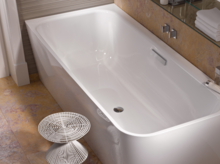 Rechteckige Badewanne aus Stahl-Email, weiß, mit abgerundeten Innenecken, modernes Badezimmer mit Handtüchern und Hocker.