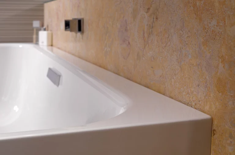 Rechteckige Badewanne aus Stahl-Email, eingepasst an Wand mit beigefarbener Fliesenoptik, modernes Design.