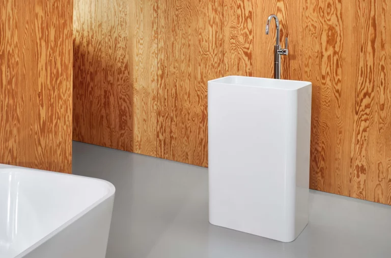 Freistehendes rechteckiges Waschbecken und rechteckige Badewanne aus Stahl-Email in modernem Badezimmer mit Holzverkleidung.