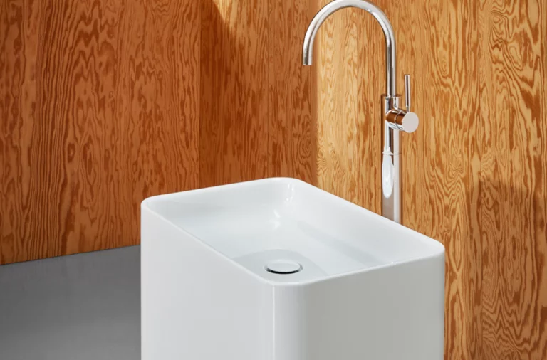 独立矩形钢瓷洗脸盆，圆角，配现代高水龙头，置于木质墙面前。