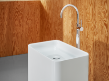 独立矩形钢瓷洗脸盆，圆角，配现代高水龙头，置于木质墙面前。