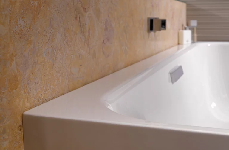 Rectangular steel-enamel bathtub with smooth edges, installed in front of patterned wall.