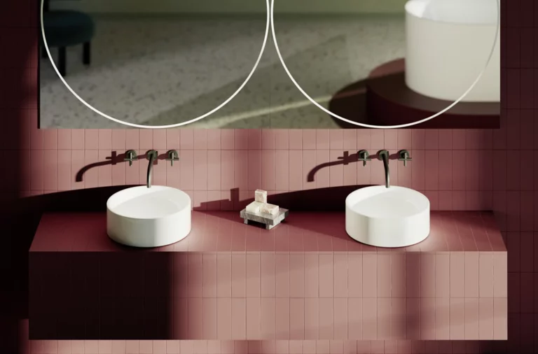 Zwei runde Aufsatzwaschbecken auf rotem Fliesentisch mit Wandarmaturen und großen runden Spiegeln im modernen Bad.
