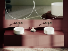 Zwei runde Aufsatzwaschbecken auf rotem Fliesentisch mit Wandarmaturen und großen runden Spiegeln im modernen Bad.