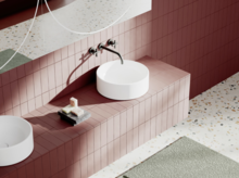 Modernes Waschbecken auf rotem Fliesentisch mit Wandarmatur, Spiegel und Seifenablage auf hellem Terrazzo-Boden.