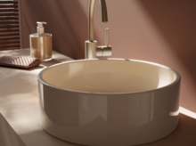 Rundes Waschbecken aus Stahl-Email auf Einbauplatte, daneben Seifenspender und Handtuch, moderne Armatur.