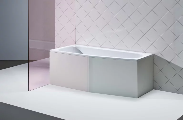 Rechteckige Badewanne aus Stahl-Email vor weiß gefliester Wand, umgeben von moderner, klarer Umgebung.