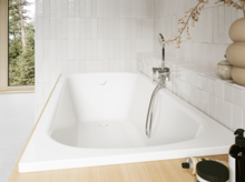 Helles Bad mit eingelassener weißer Badewanne, Fenster, Wandarmatur, Handbrause, Ablage und Pflegeprodukten.