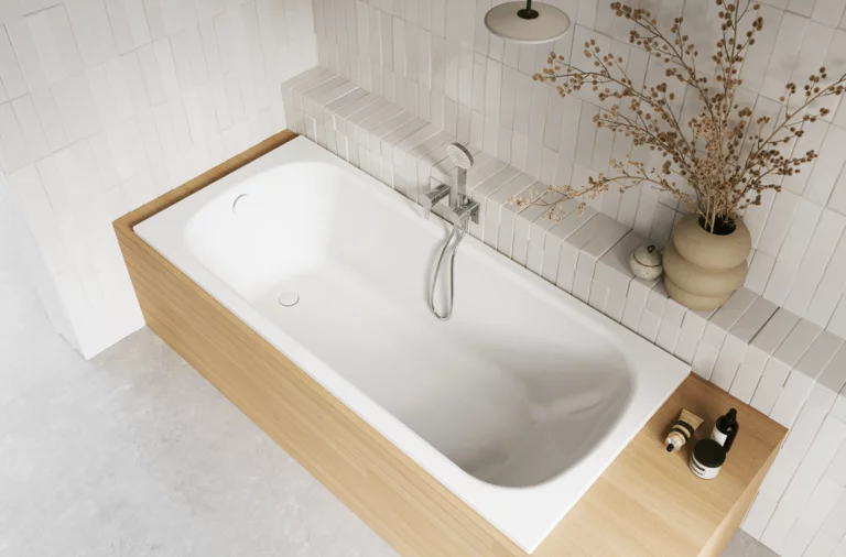 Aufsicht auf helles Bad mit eingelassener weißer Badewanne, beiger Einfassung, Armatur, Vase und Pflegeprodukten.