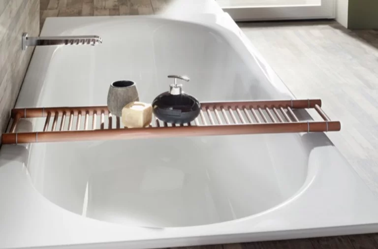 Rectangular steel enamel bathtub, glossy white, with wooden tray and bathroom accessories, in modern bathroom.