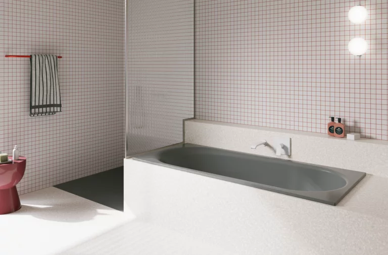 Grey glazed titanium-steel bathtub in a bright bathroom with white tiles, wall faucet and open shower.