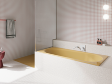 Yellow glazed titanium-steel bathtub in a bright bathroom with white tiles, wall faucet and open shower.