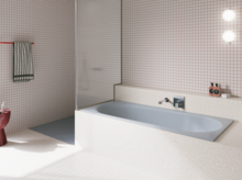Light blue glazed titanium-steel bathtub in a bright bathroom with white tiles, wall faucet and open shower.